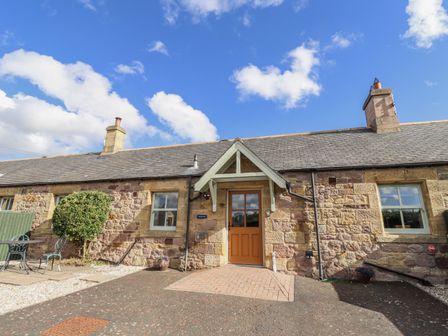 A house with a front door and garden seating at Rosefinch in Lucker