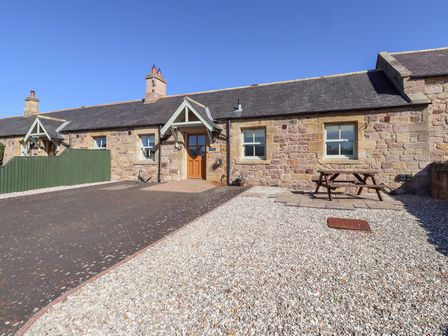 An outdoor area with a stone cottage and picnic table at Chaffinch in Lucker