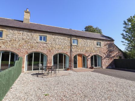 A stone house with a table and chairs outside at Bullfinch in Lucker