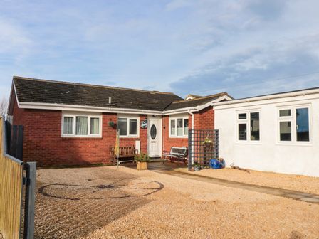 A single-story building with red brick and white walls and a gravel driveway at Arcadie in Amble