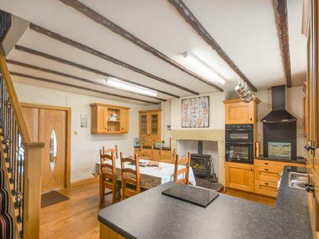 A kitchen and dining area with wooden cabinets wooden dining table and chairs and a wood stove at Creel Cottage Amble