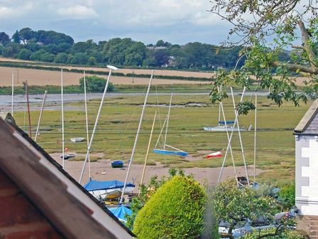 A view of sailboats on a marshland with a field and trees in the background at Baysyde in Alnmouth