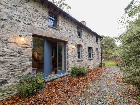 A stone house exterior with blue framed windows and door surrounded by fallen leaves and plants at Castle Coach House in Newport Pembrokeshire