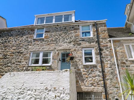 A stone house with white framed windows and a blue door at Cormorant Cottage in St Ives