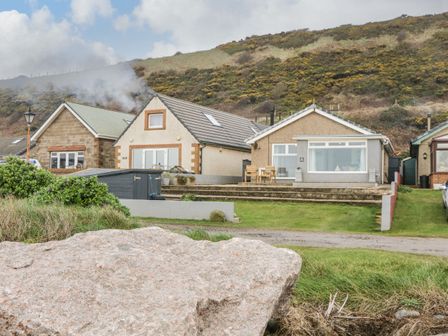 A row of houses with grassy yards and a large rock in the foreground at The Chalet in Coulderton near Egremont Cumbria