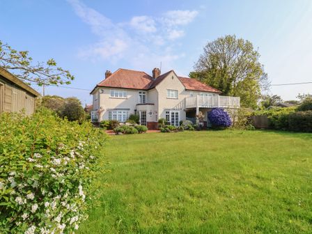 A two-story house with a red tiled roof and white walls with a large green lawn and garden at halsey in walberswick