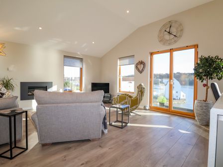 A living room with sofas a large window and a clock on the wall at The Penthouse in Woodbridge