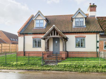 A front view of a house with a tiled roof two dormer windows and a wooden porch at Hillside Cottage in Beeston near Necton