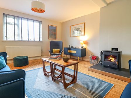 A living room with a wood stove and coffee table at The Wardens House in Tregynon near Newtown
