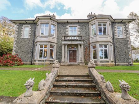 A stone house with a front door and windows and stairs with dragon sculptures at The Lloyd George in Bontnewydd Gwynedd