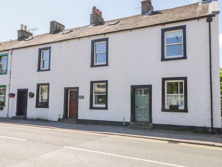 A street view of a row of white cottages with dark door and window frames at The Old Betting Shop in Keswick
