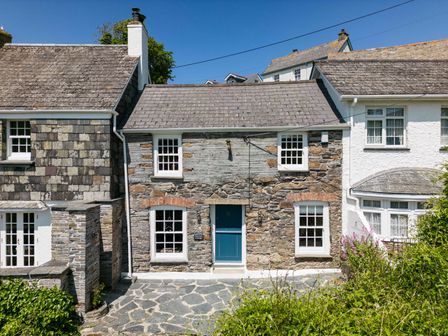 A stone cottage with a blue door and white framed windows at Mermaid Cottage in Port Isaac
