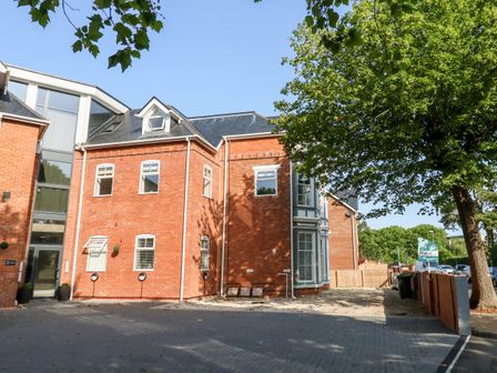 A red brick residential building with multiple windows and a paved driveway near a tree at Flat 6 Thornlow Heights in Weymouth
