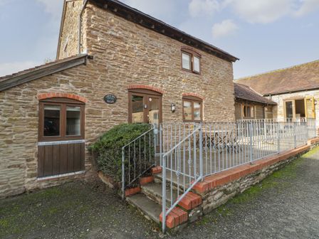 Exterior view of a stone cottage with wooden windows and a metal railing at Larch Bed Cottage Stanford Bishop near Bromyard