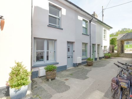 A row of houses with potted plants near the doors and bicycles parked on the side at The Cottage on The Square in Chagford