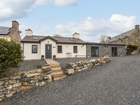 A single story house with stone and white walls and a gravel driveway at Tan Y Coed - Nasareth Nasareth near Penygroes