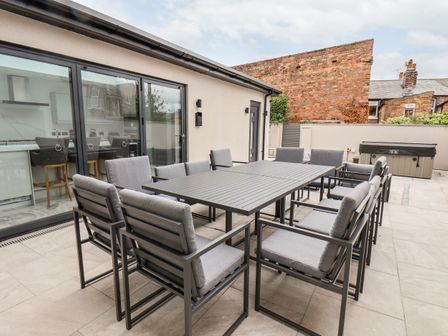 An outdoor patio area with a large rectangular table and twelve cushioned chairs at Church View Scarborough