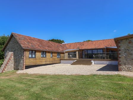 A house with a deck and yard at The Stables in Uplyme