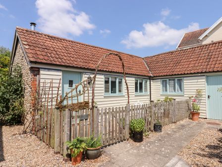 A small courtyard with potted plants a wooden fence a light blue door and windows and a tiled roof at The Calf Pen in Colyton