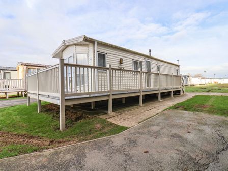 A mobile home with beige railing on a concrete and grassy area at Forest Star in Cayton