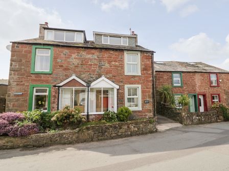 Two red brick houses with green and white window frames and small front gardens at Wainwright Cottage in Gosforth
