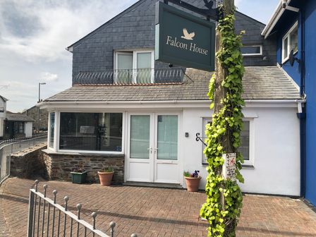 A building with a sign that says Falcon House and a vine growing on a post in front at Falcon House in Tintagel