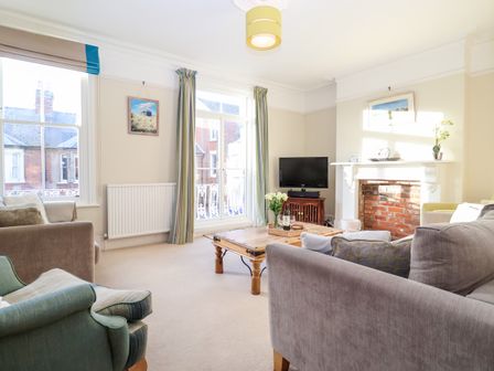 A living room with sofas a coffee table a fireplace a television and large windows at Elkhorn in Southwold