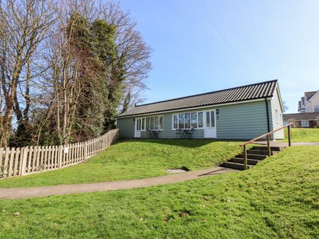 A single-story building with a tiled roof lawn and trees at 15 The Dell in Mundesley