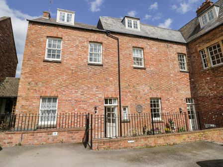 Exterior view of a two story brick building with white framed windows and doors behind a black metal fence at 4 The Old Council House Shipston-On-Stour