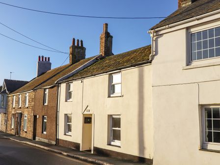 A row of terraced houses along a street with chimneys on the roofs at By-sea in Marazion