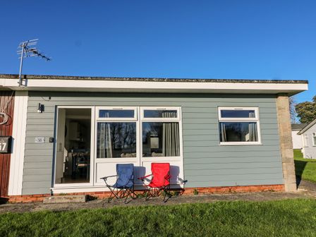 A small house with two folding chairs outside on grass at Beachcomber in Norton Park near Dartmouth