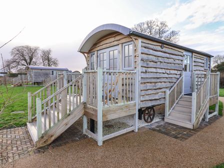 Two wooden shepherd huts with stairs and railings on grassy land at The Fenton in Bolton Percy near Tadcaster