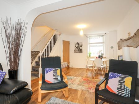 A living room with chairs a dining table stairs and a wooden floor at 5 Thomas Street in Llanberis