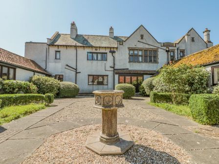 An exterior courtyard with a stone pedestal and surrounding shrubbery at Highcliffe Manor in Flamborough