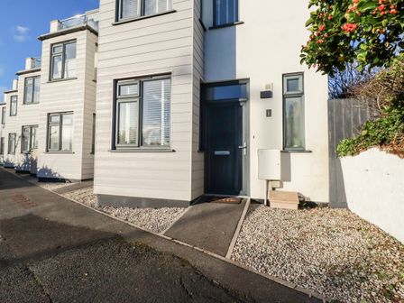 Entrance of a modern house with windows a blue door gravel areas and a pathway at Chy Fistral in Newquay