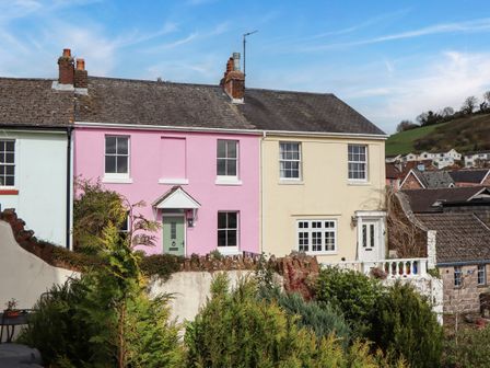 A row of three houses with colorful facades and greenery in the foreground at Rose Cottage in Bishopsteignton