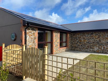 An outdoor patio area with stone walls wooden fencing and a gate at Bimbling Cottage Portreath near Illogan