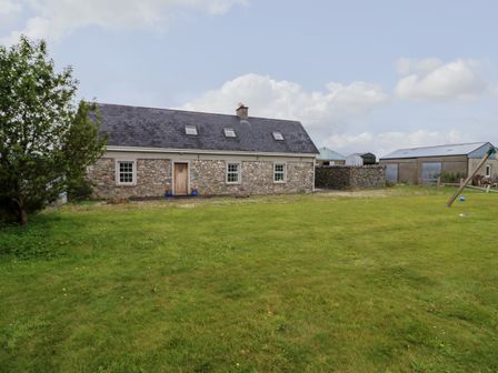 A stone farmhouse with a slate roof and three skylights in a grassy yard at Glebe Farmhouse Listry near Killarney County Kerry