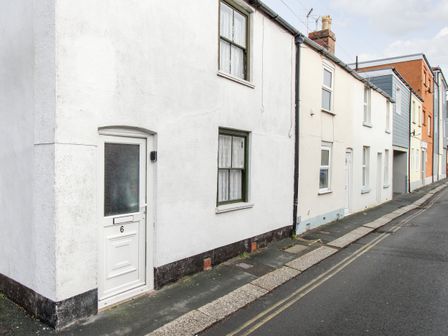 A street view of terraced houses with white doors and windows at Angel Cottage in Weymouth