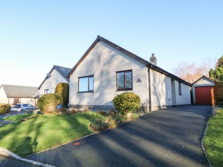 A bungalow with a driveway and garden in front and a garage at Bedfelltan in Talybont