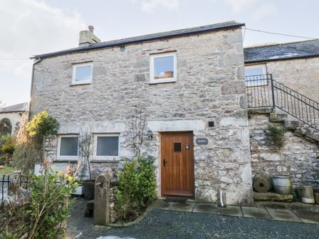 Stone cottage with wooden door and small garden in front at Granary Bardsea