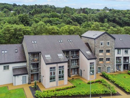 A residential building with balconies and large windows surrounded by greenery at Bruach in Backbarrow