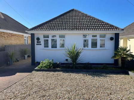 A bungalow with a tiled roof and gravel front garden with plants at The Willows in Preston Weymouth
