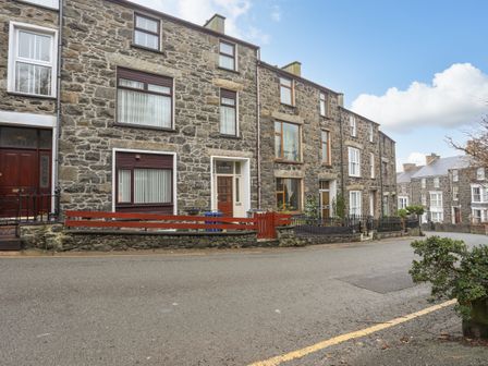 Stone terraced houses along a street with plants and fences at Hillside Apartment in Pwllheli
