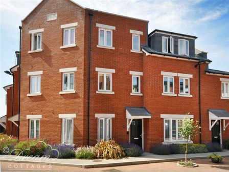 A three-story red brick residential building with multiple white-framed windows and black doors at Admiral's Quarter Apartment 5 in Weymouth
