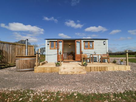 A small cabin with wooden deck and outdoor seating with hot tub outside at Buzzards in Morchard Bishop