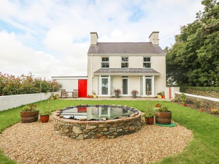 A two story house with a stone pond and garden in front at Bryn Tirion in Llangefni