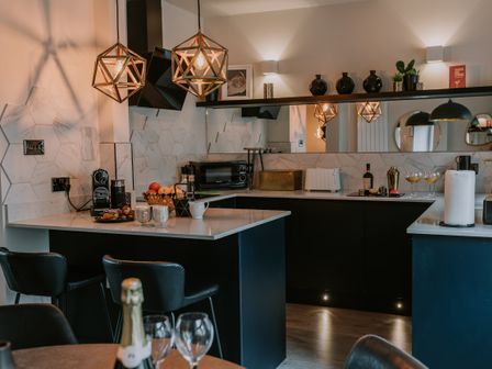 A kitchen with black cabinets white countertops pendant lights and various kitchen appliances at 37 Jubilee Street in Llandudno