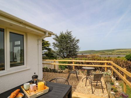 A patio with a table set with croissants juice and cups and a gravel area with two small tables and chairs outside Bryn Alaw in Newport Pembrokeshire