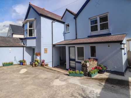 Exterior of a light blue painted house with flower pots around the entrance at Ty Post Newport Pembrokeshire